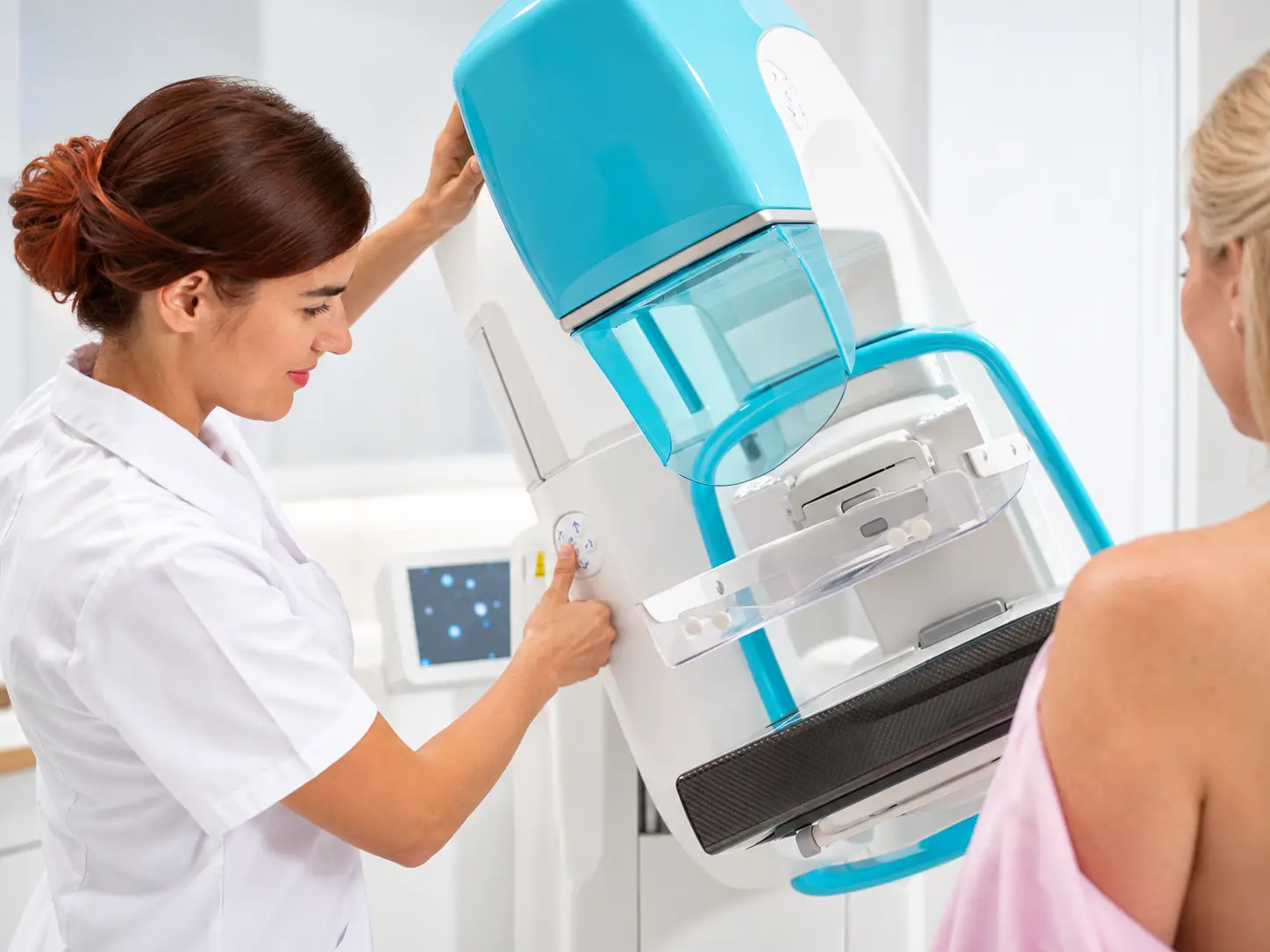 Tecnico sanitario regola il mammografo per acquisire diverse proiezioni mammografiche